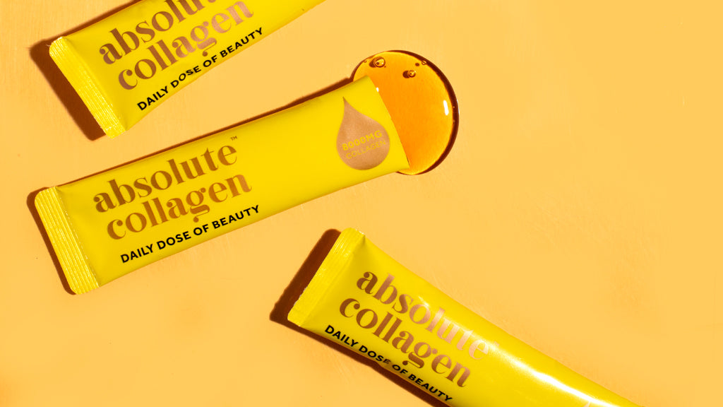 3 sachets d'élixir de collagène sur une table, dont un ouvert et dont le contenu s'étale